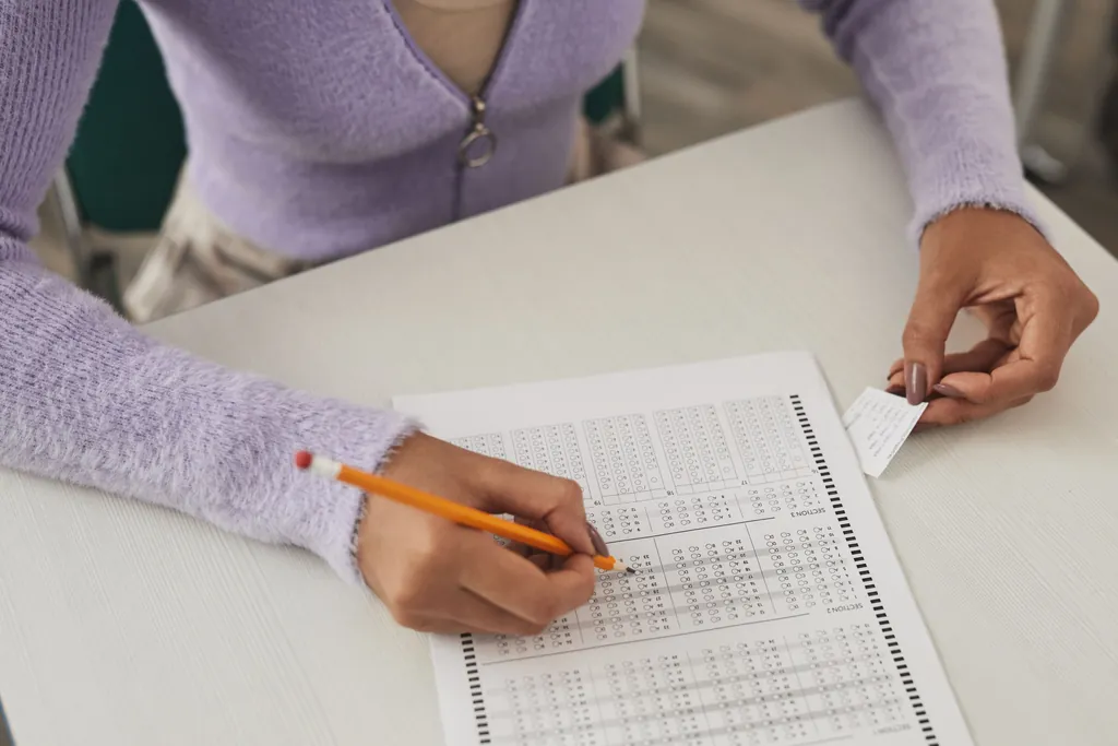 Hands filling in an answer sheet with a pencil