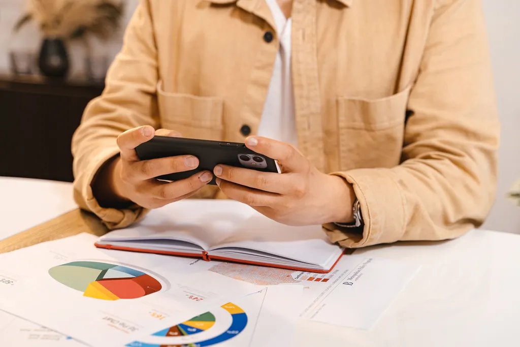 Hands holding a phone over an open notebook