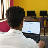 Young man at a laptop with a registration form on screen